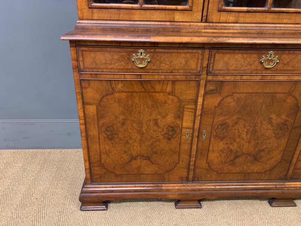 A large three-door burr walnut bookcase with glazed upper doors, three frieze drawers, and crossbanded cupboard doors below. View III