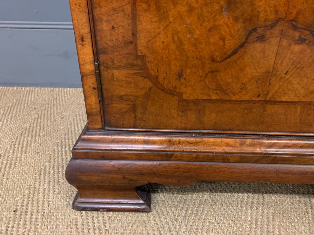 A large three-door burr walnut bookcase with glazed upper doors, three frieze drawers, and crossbanded cupboard doors below. View V