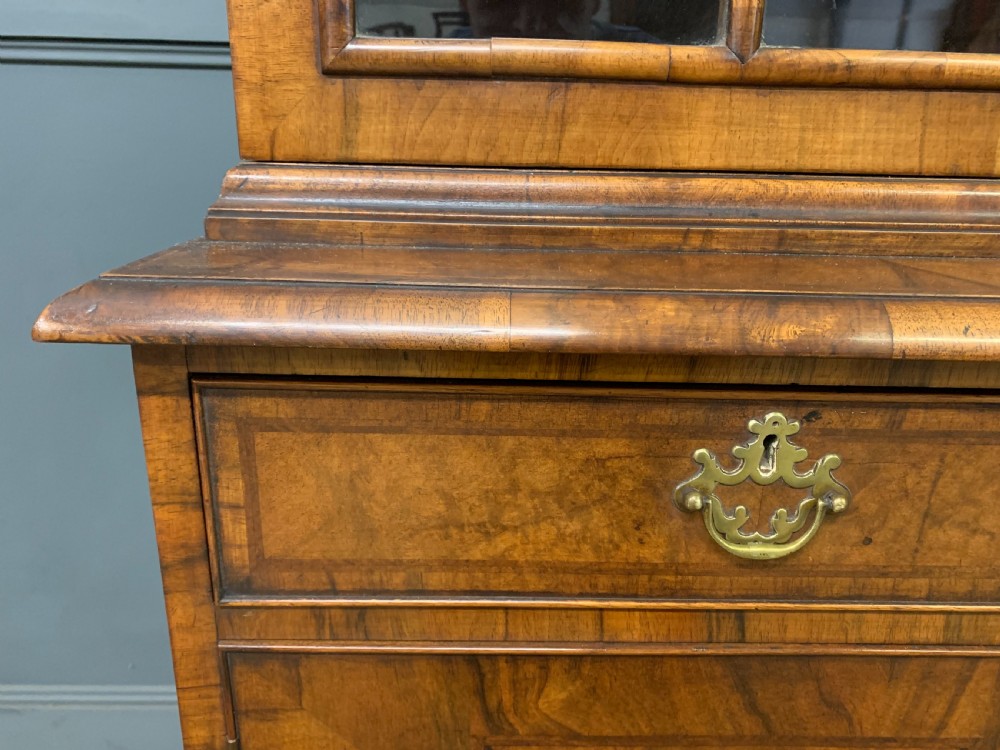 A large three-door burr walnut bookcase with glazed upper doors, three frieze drawers, and crossbanded cupboard doors below. View VI