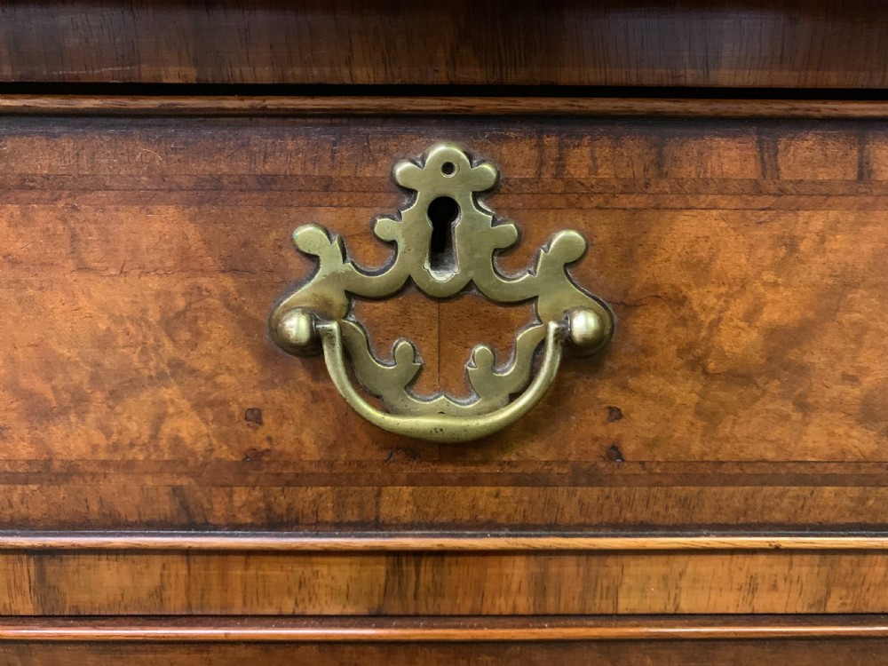 A large three-door burr walnut bookcase with glazed upper doors, three frieze drawers, and crossbanded cupboard doors below. View VIII