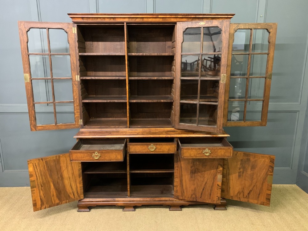 A large three-door burr walnut bookcase with glazed upper doors, three frieze drawers, and crossbanded cupboard doors below. View XI