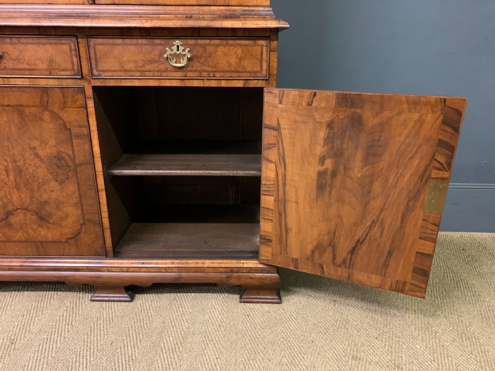 A large three-door burr walnut bookcase with glazed upper doors, three frieze drawers, and crossbanded cupboard doors below. View XII