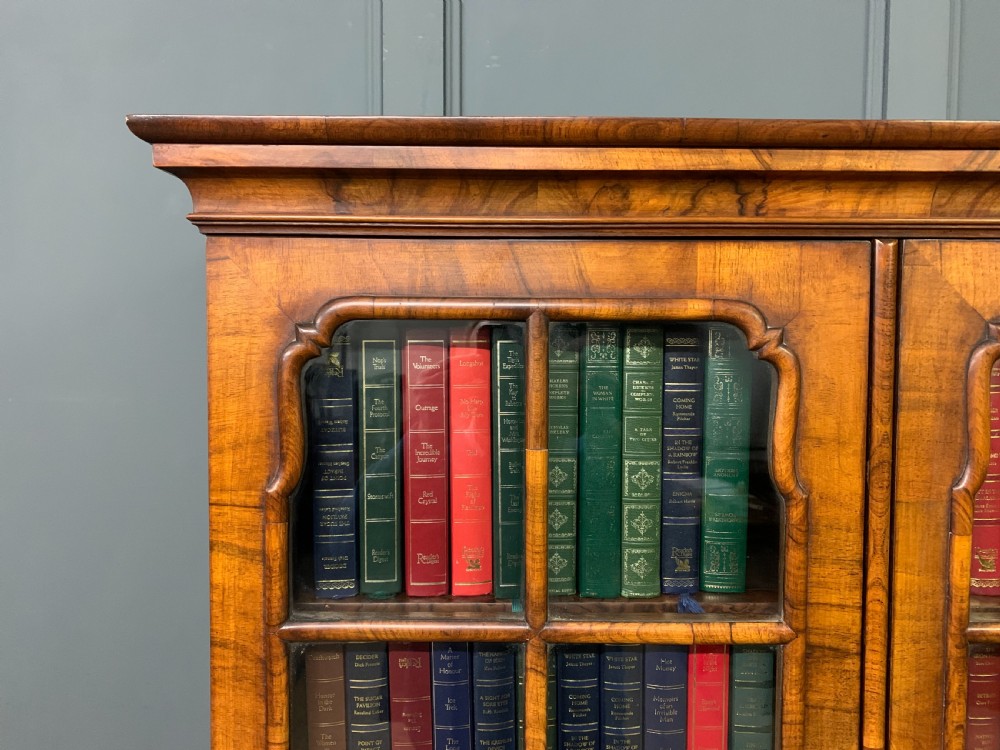 A large three-door burr walnut bookcase with glazed upper doors, three frieze drawers, and crossbanded cupboard doors below. View XVII