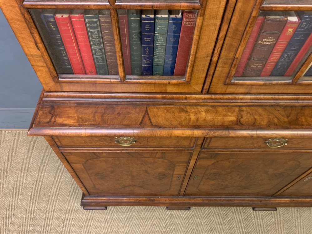 A large three-door burr walnut bookcase with glazed upper doors, three frieze drawers, and crossbanded cupboard doors below. View XVIII