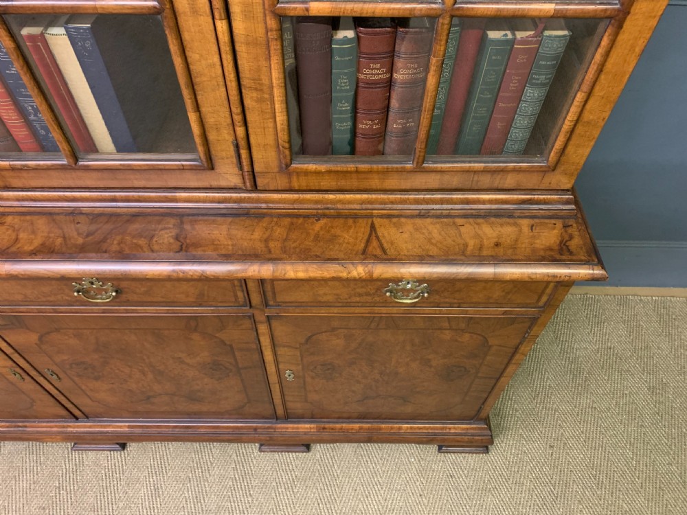 A large three-door burr walnut bookcase with glazed upper doors, three frieze drawers, and crossbanded cupboard doors below. View XIX