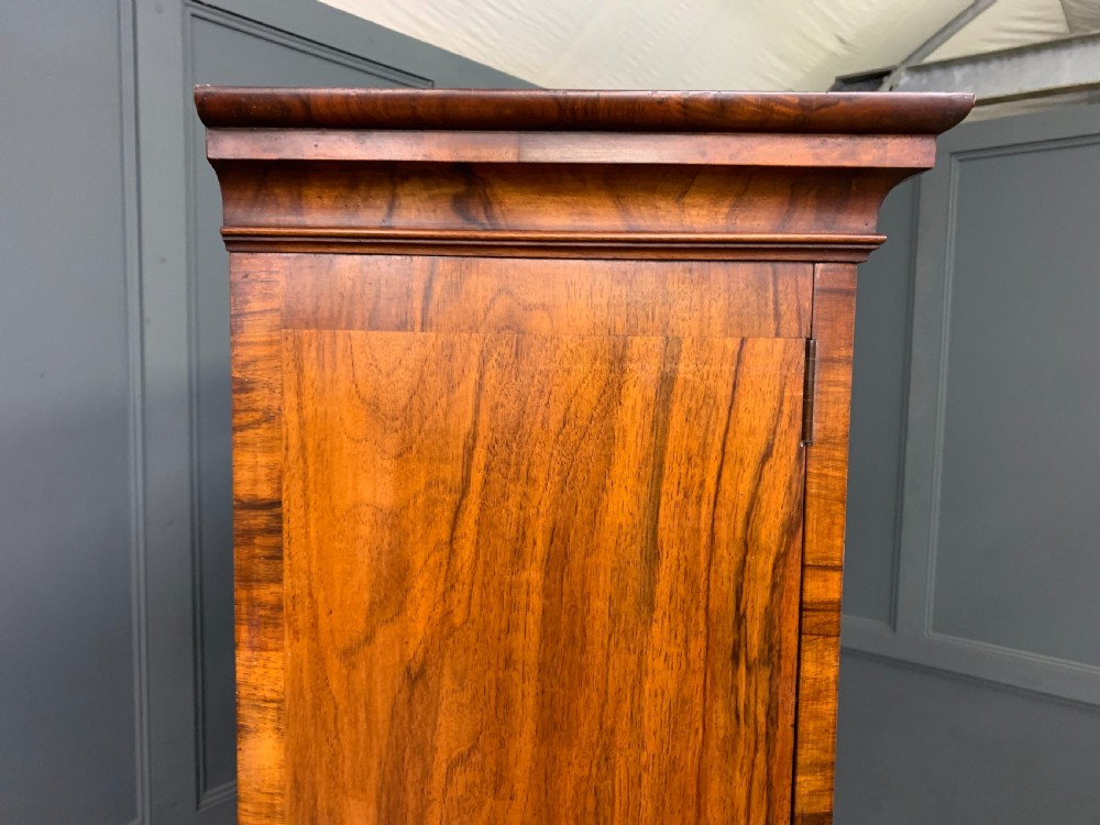 A large three-door burr walnut bookcase with glazed upper doors, three frieze drawers, and crossbanded cupboard doors below. View XXIII