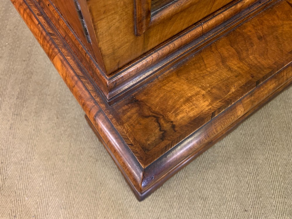 A large three-door burr walnut bookcase with glazed upper doors, three frieze drawers, and crossbanded cupboard doors below. View XXV