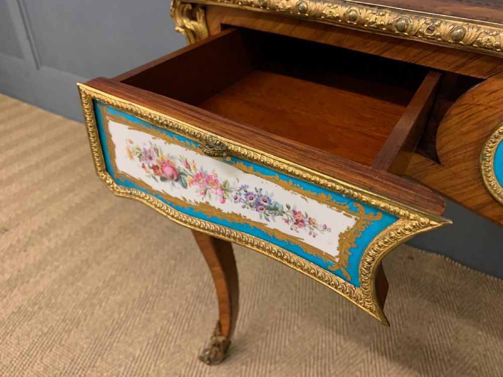 An antique Louis XV style French tulipwood bureau plat featuring a leather-inset top, gilt-bronze mounts, cabriole legs, and hand-painted porcelain plaques. View VIII