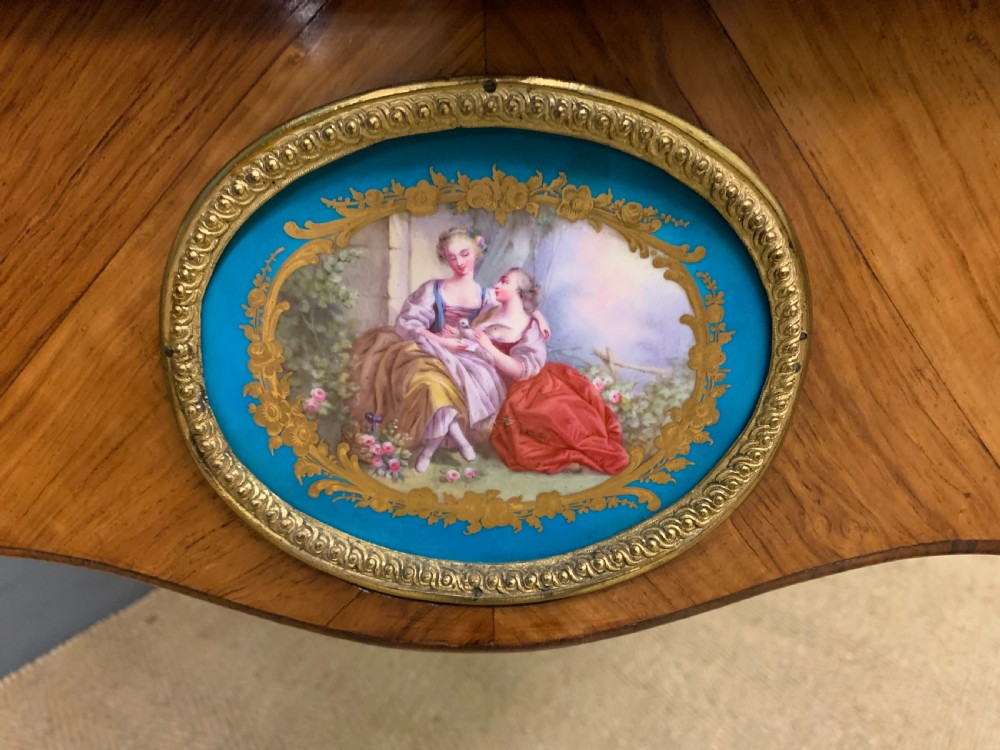 An antique Louis XV style French tulipwood bureau plat featuring a leather-inset top, gilt-bronze mounts, cabriole legs, and hand-painted porcelain plaques. View XII