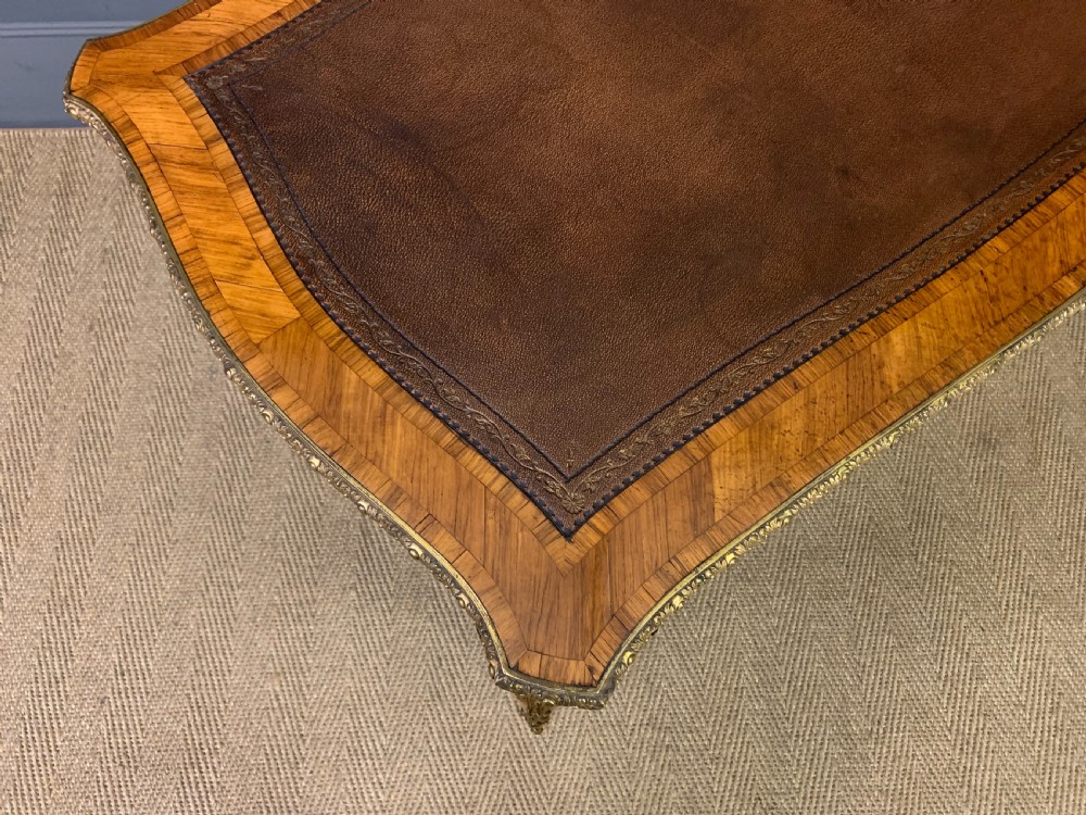 An antique Louis XV style French tulipwood bureau plat featuring a leather-inset top, gilt-bronze mounts, cabriole legs, and hand-painted porcelain plaques. View XIII