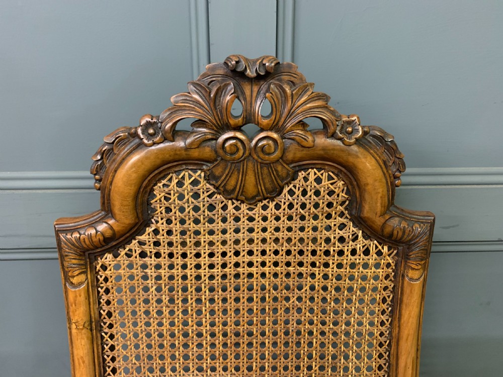 A pair of carved walnut side chairs with tall woven cane backs, floral tapestry upholstered seats, and scroll legs. View VI