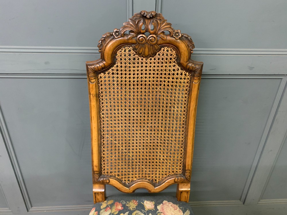 A pair of carved walnut side chairs with tall woven cane backs, floral tapestry upholstered seats, and scroll legs. View X