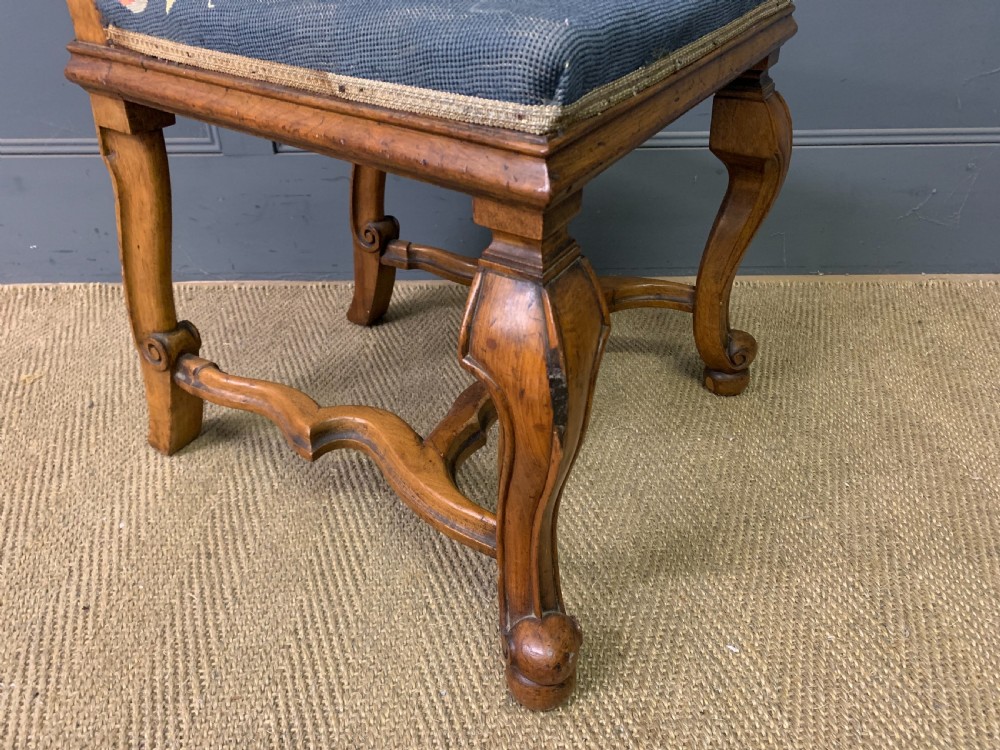 A pair of carved walnut side chairs with tall woven cane backs, floral tapestry upholstered seats, and scroll legs. View XVII