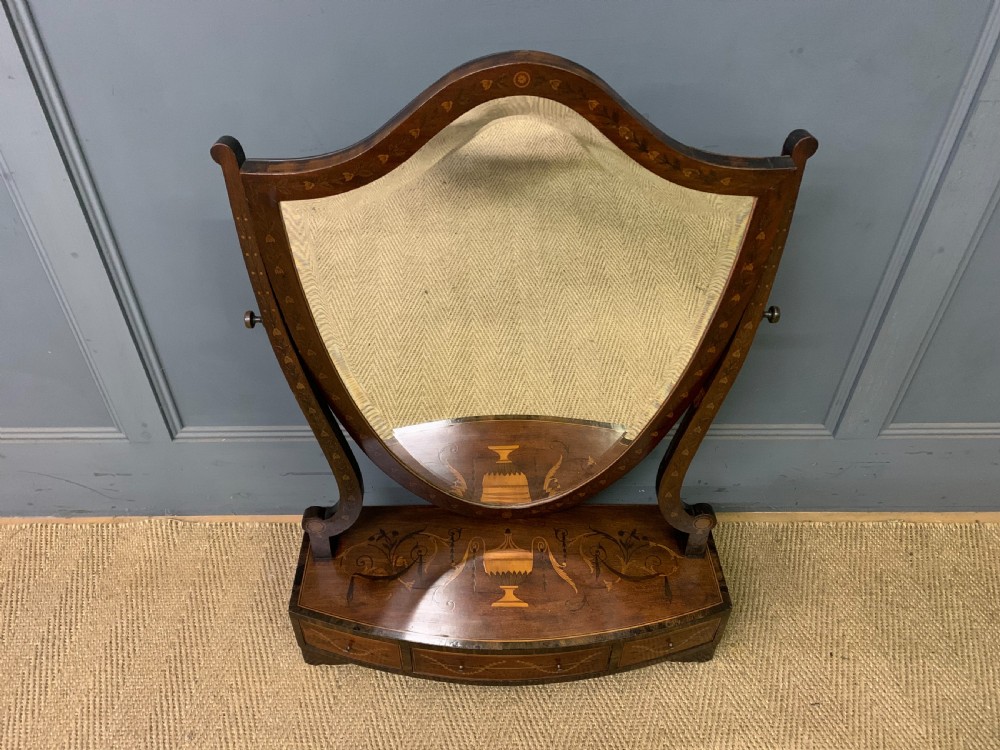 A Georgian mahogany toilet mirror featuring a shield-shaped swing frame, inlaid satinwood urn motifs, and a drawer base with curved fronting. View II