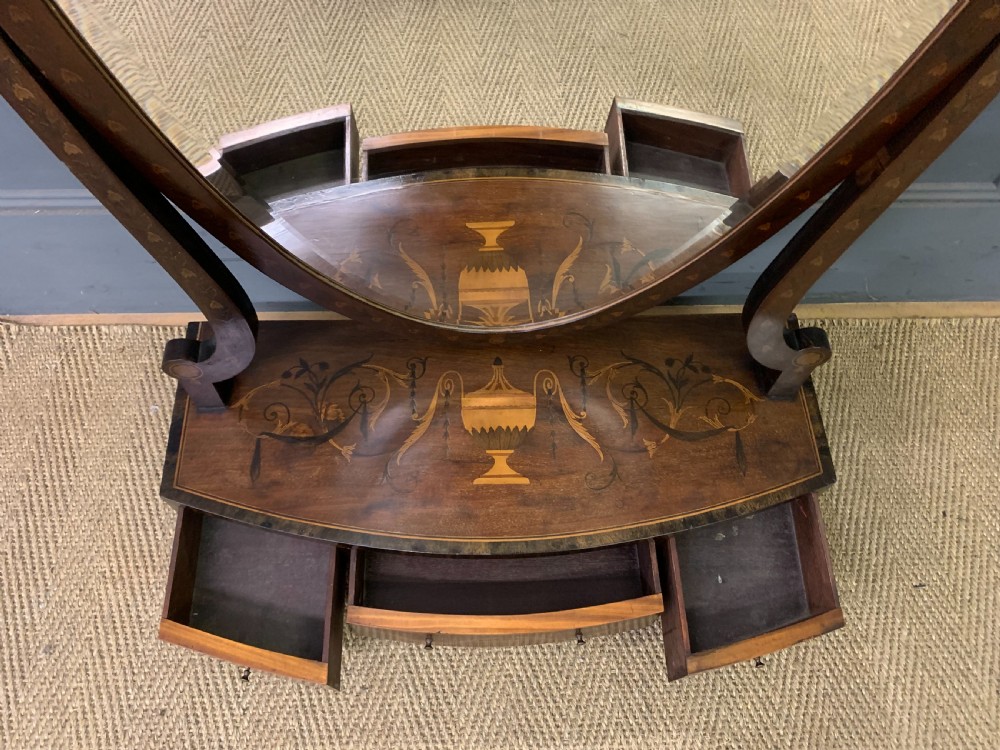 A Georgian mahogany toilet mirror featuring a shield-shaped swing frame, inlaid satinwood urn motifs, and a drawer base with curved fronting. View IV
