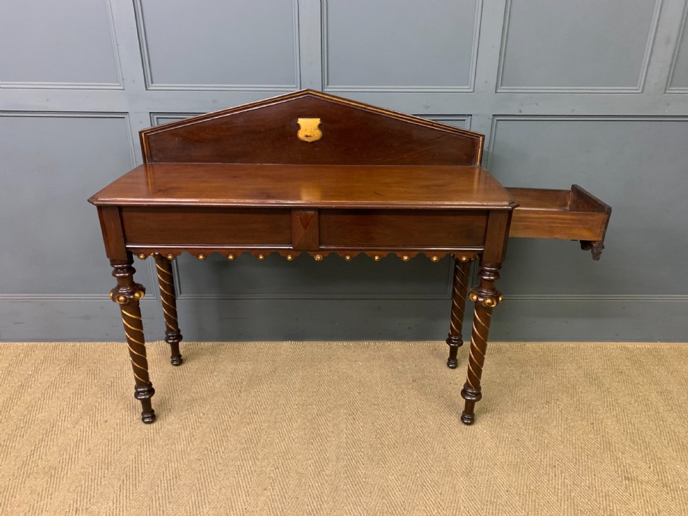 A dark mahogany Victorian hall table featuring spiral turned legs with gold accents, a scalloped apron, and an elevated gallery back with a central brass crest. View II