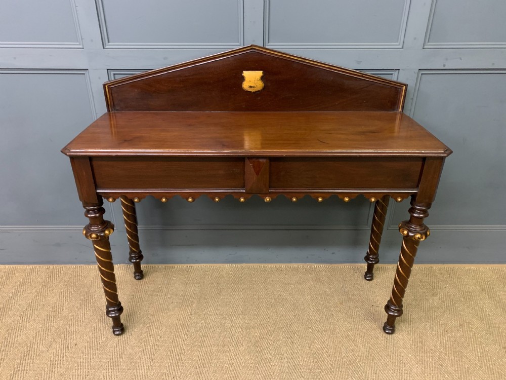 A dark mahogany Victorian hall table featuring spiral turned legs with gold accents, a scalloped apron, and an elevated gallery back with a central brass crest. View III
