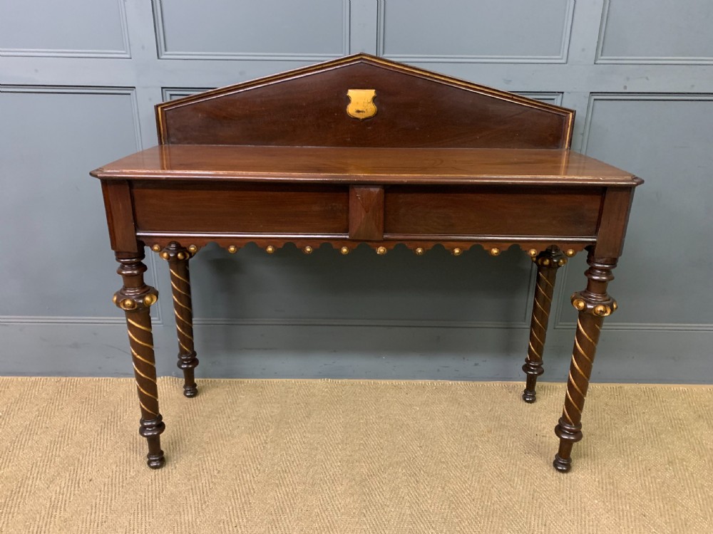 A dark mahogany Victorian hall table featuring spiral turned legs with gold accents, a scalloped apron, and an elevated gallery back with a central brass crest. View IV