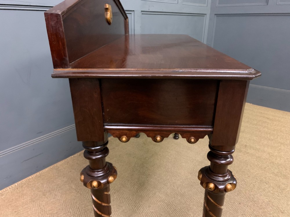 A dark mahogany Victorian hall table featuring spiral turned legs with gold accents, a scalloped apron, and an elevated gallery back with a central brass crest. View XII