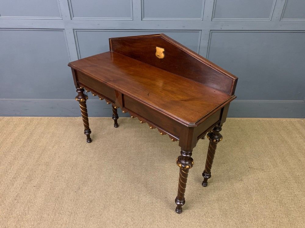 A dark mahogany Victorian hall table featuring spiral turned legs with gold accents, a scalloped apron, and an elevated gallery back with a central brass crest. View XV