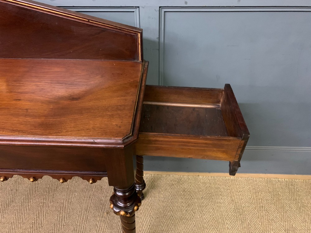 A dark mahogany Victorian hall table featuring spiral turned legs with gold accents, a scalloped apron, and an elevated gallery back with a central brass crest. View XVII