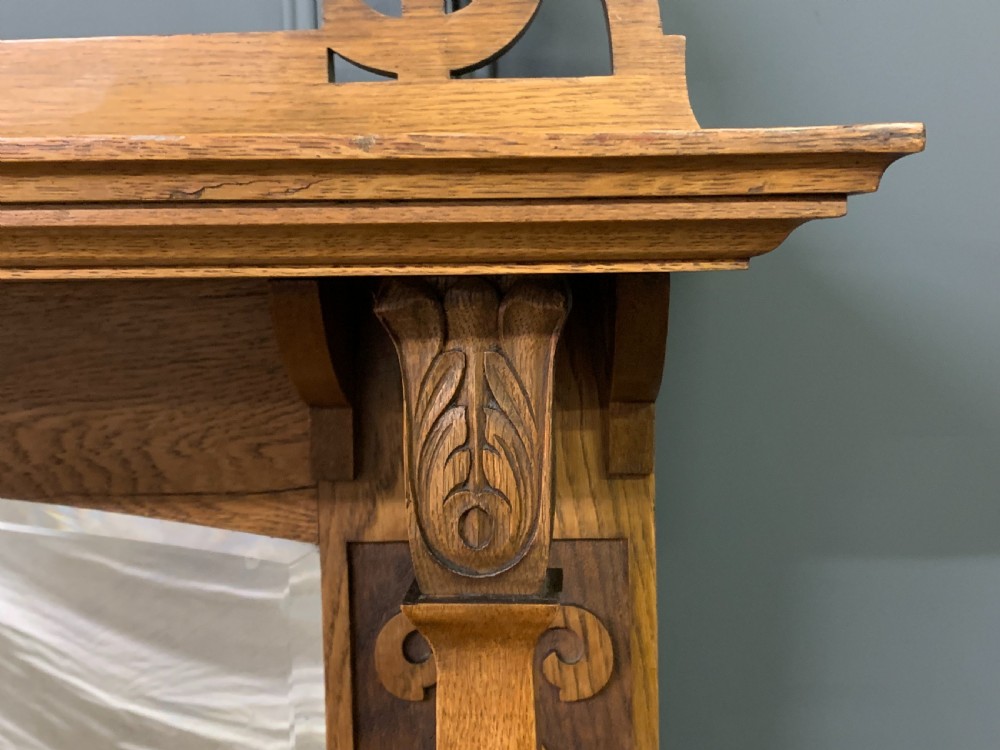 An Arts and Crafts golden oak sideboard featuring a mirrored superstructure with carved fretwork and blue ceramic cabochons above two drawers and two cupboard doors. View IX
