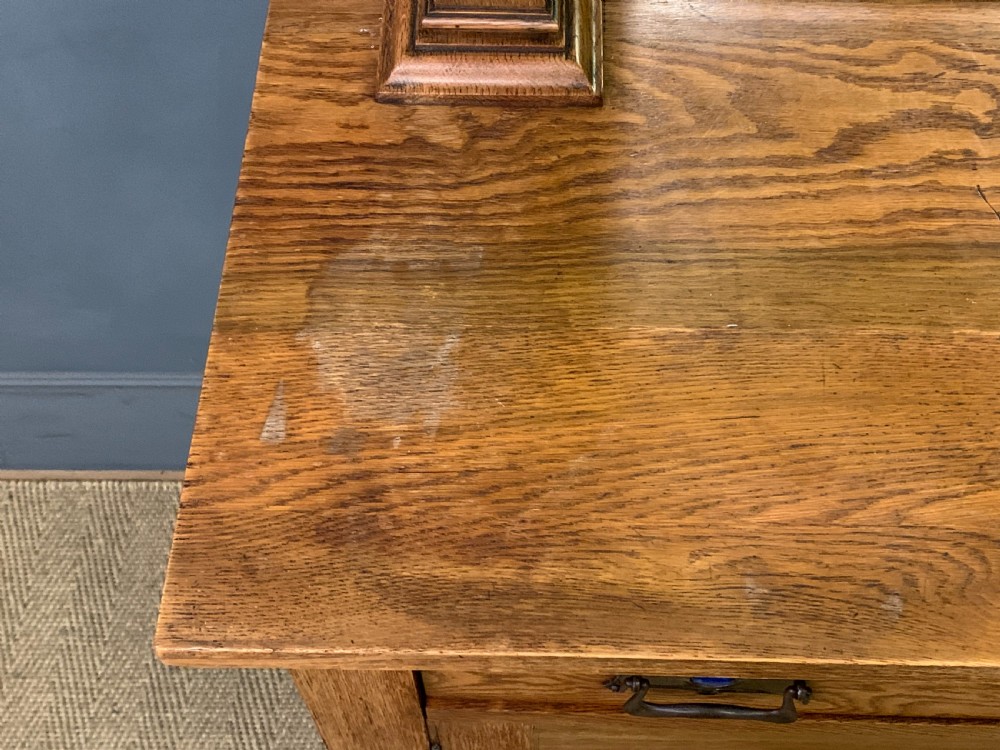An Arts and Crafts golden oak sideboard featuring a mirrored superstructure with carved fretwork and blue ceramic cabochons above two drawers and two cupboard doors. View XII