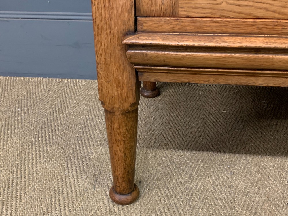 An Arts and Crafts golden oak sideboard featuring a mirrored superstructure with carved fretwork and blue ceramic cabochons above two drawers and two cupboard doors. View XX