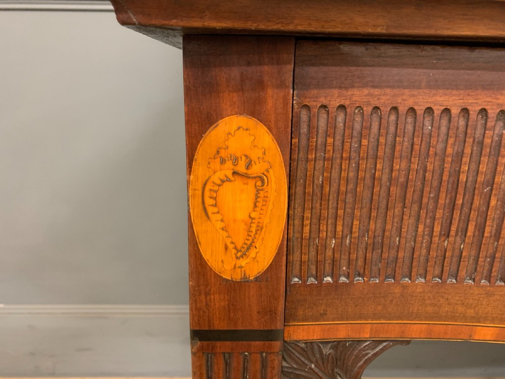 A George III mahogany serving table featuring a serpentine front, inlaid fluted detailing, square tapered legs, and a brass gallery rail. View V