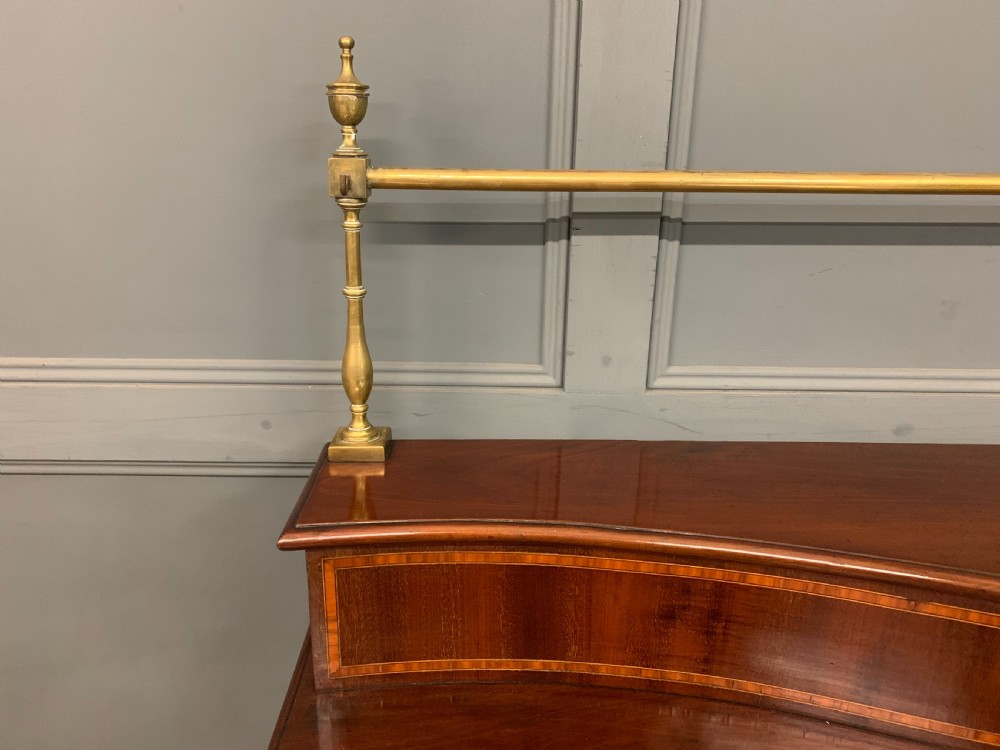 A George III mahogany serving table featuring a serpentine front, inlaid fluted detailing, square tapered legs, and a brass gallery rail. View IX