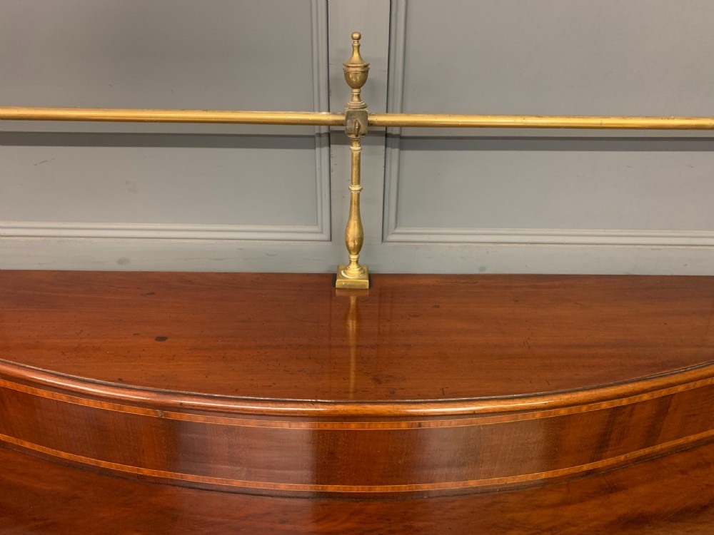 A George III mahogany serving table featuring a serpentine front, inlaid fluted detailing, square tapered legs, and a brass gallery rail. View X