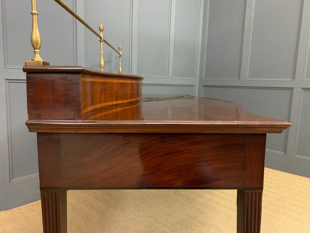A George III mahogany serving table featuring a serpentine front, inlaid fluted detailing, square tapered legs, and a brass gallery rail. View XV