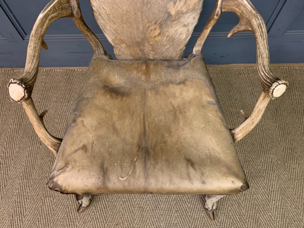 A nineteenth-century armchair constructed from natural stag antlers with a natural hide upholstered seat and backrest, featuring hoof legs. View III