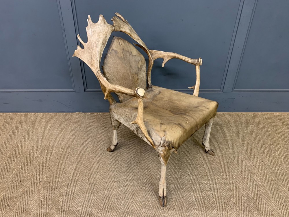 A nineteenth-century armchair constructed from natural stag antlers with a natural hide upholstered seat and backrest, featuring hoof legs. View VI