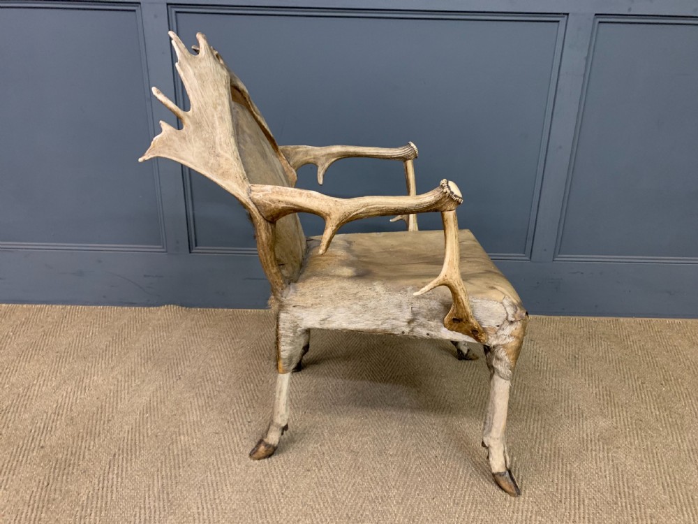 A nineteenth-century armchair constructed from natural stag antlers with a natural hide upholstered seat and backrest, featuring hoof legs. View VIII