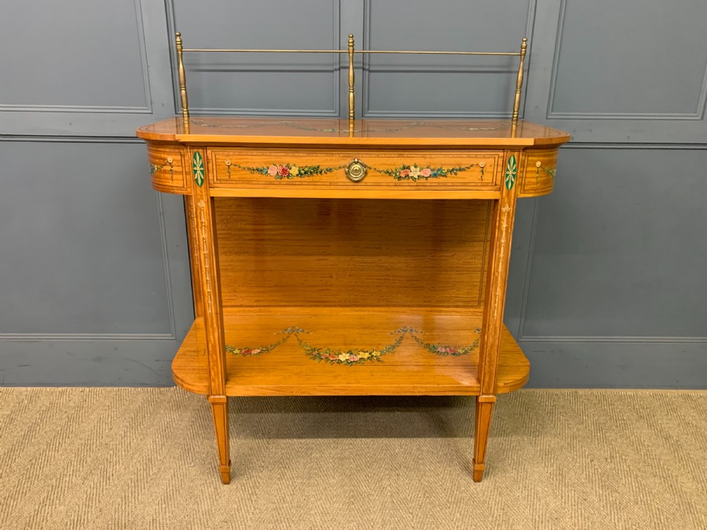 A painted satinwood side table featuring hand-painted floral swags, a single drawer, a lower shelf, tapered square legs, and a raised brass gallery rail. View II