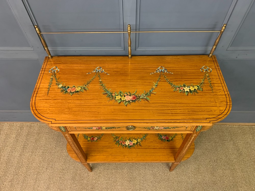 A painted satinwood side table featuring hand-painted floral swags, a single drawer, a lower shelf, tapered square legs, and a raised brass gallery rail. View IV