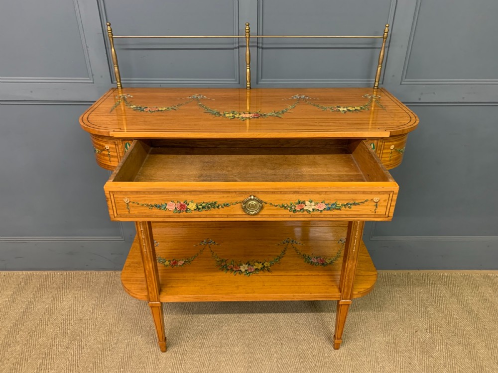 A painted satinwood side table featuring hand-painted floral swags, a single drawer, a lower shelf, tapered square legs, and a raised brass gallery rail. View XIV