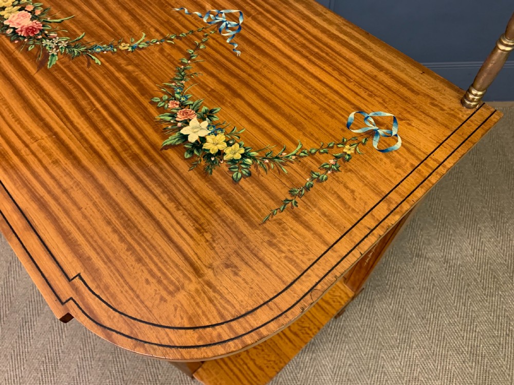 A painted satinwood side table featuring hand-painted floral swags, a single drawer, a lower shelf, tapered square legs, and a raised brass gallery rail. View XX