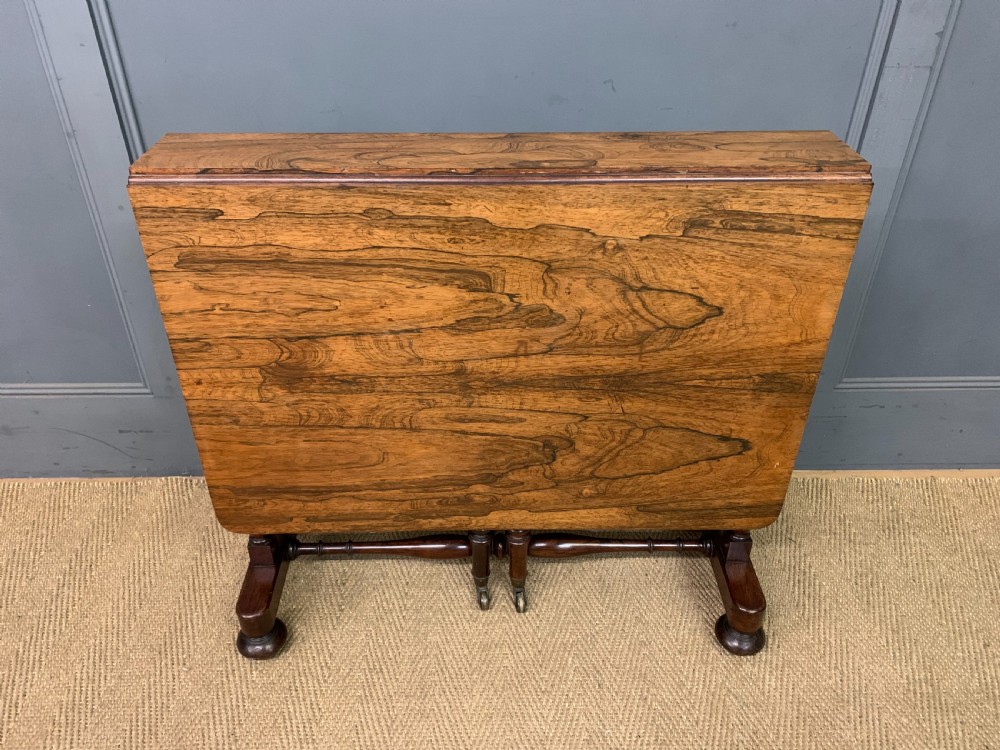 A William IV rosewood Sutherland table featuring folded drop-leaf sides, turned supports, and platform feet with castors. View II