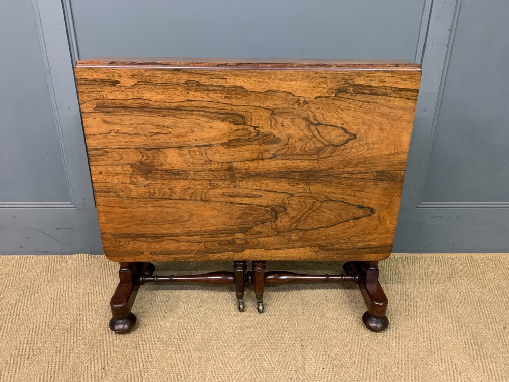 A William IV rosewood Sutherland table featuring folded drop-leaf sides, turned supports, and platform feet with castors. View III