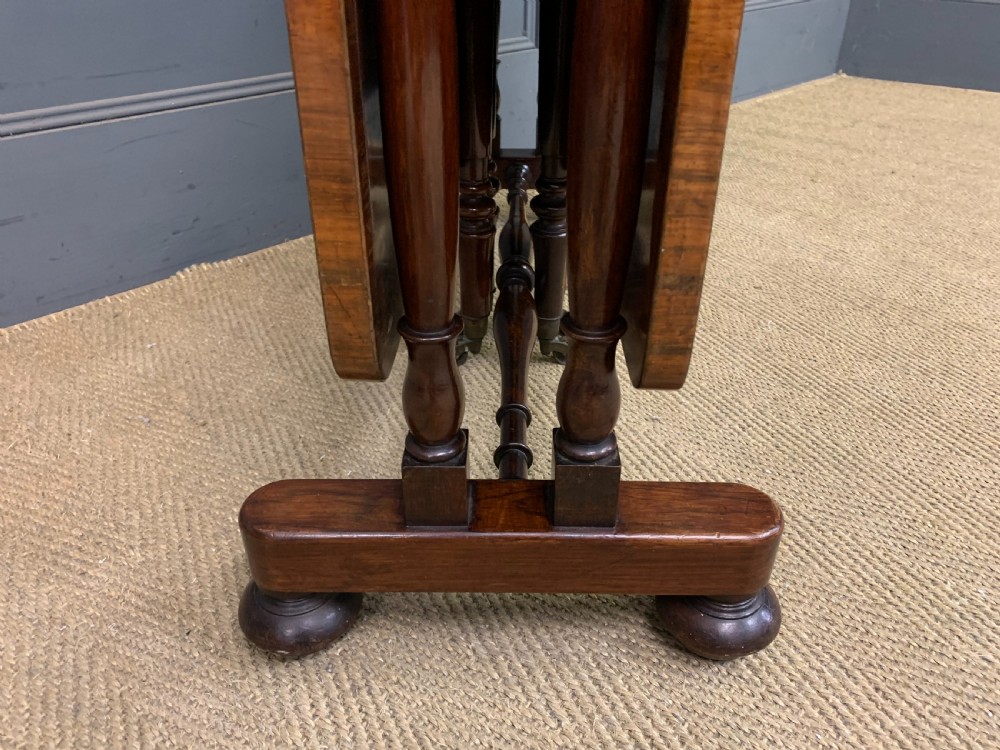 A William IV rosewood Sutherland table featuring folded drop-leaf sides, turned supports, and platform feet with castors. View VI