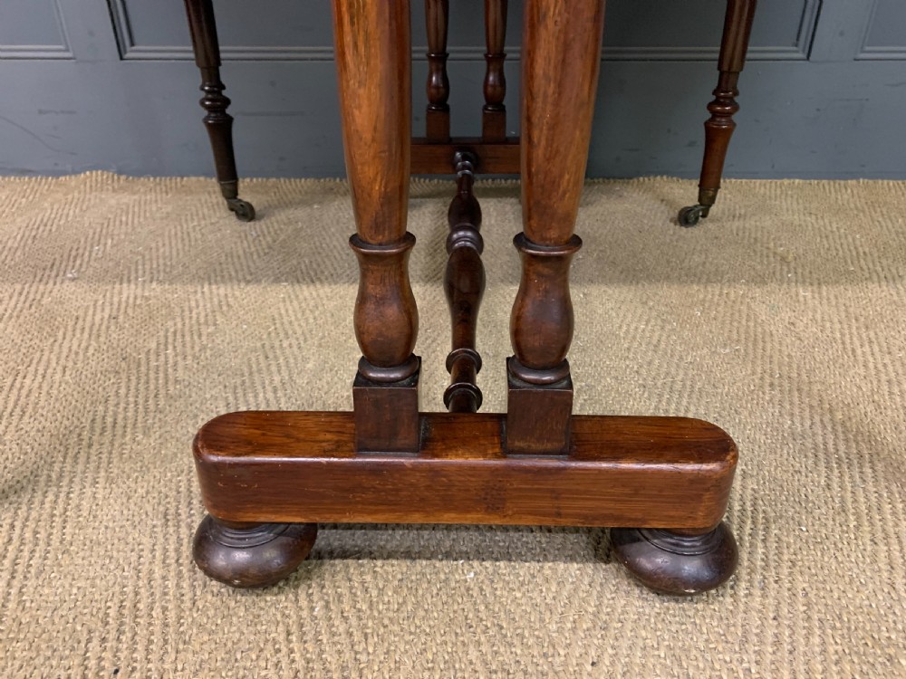 A William IV rosewood Sutherland table featuring folded drop-leaf sides, turned supports, and platform feet with castors. View X