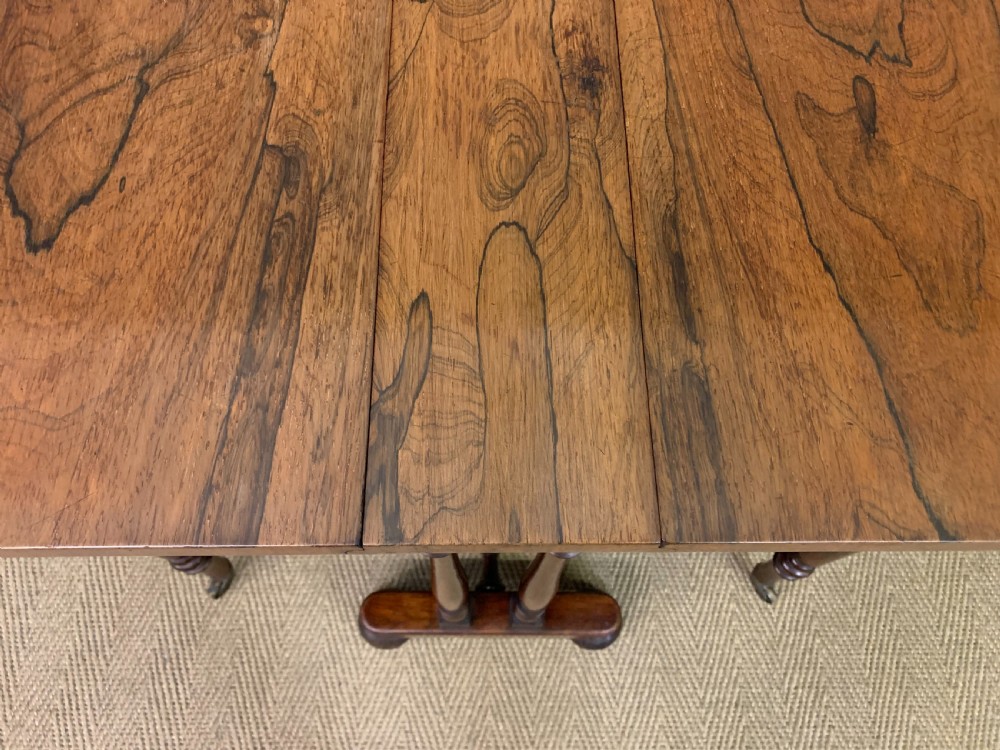 A William IV rosewood Sutherland table featuring folded drop-leaf sides, turned supports, and platform feet with castors. View XIV