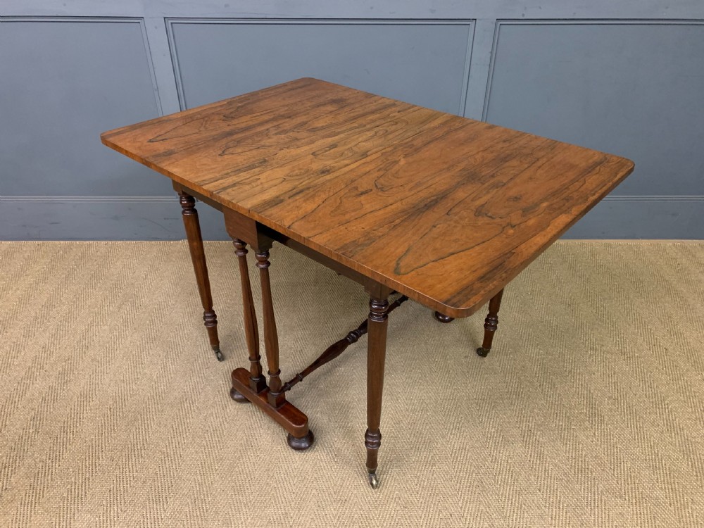 A William IV rosewood Sutherland table featuring folded drop-leaf sides, turned supports, and platform feet with castors. View XVI