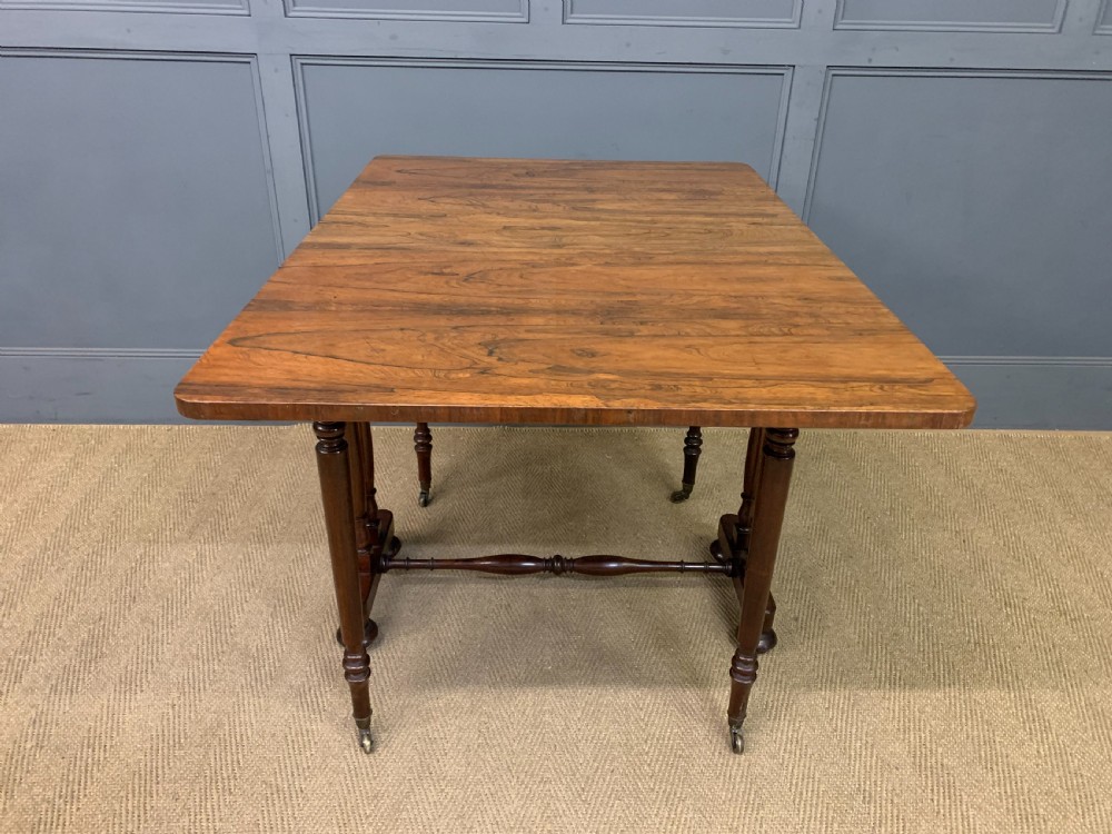 A William IV rosewood Sutherland table featuring folded drop-leaf sides, turned supports, and platform feet with castors. View XVII