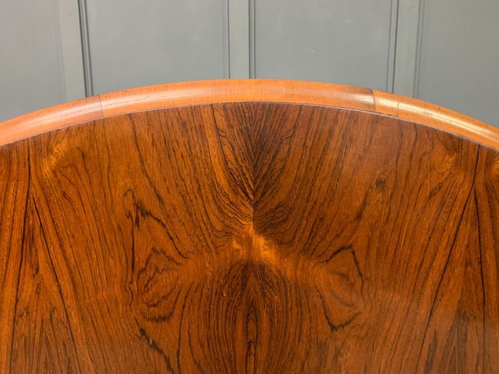 An oval Victorian rosewood loo table featuring a book-matched veneered top, crossbanded edge, and a carved central pedestal with four splayed legs on castors. View XI