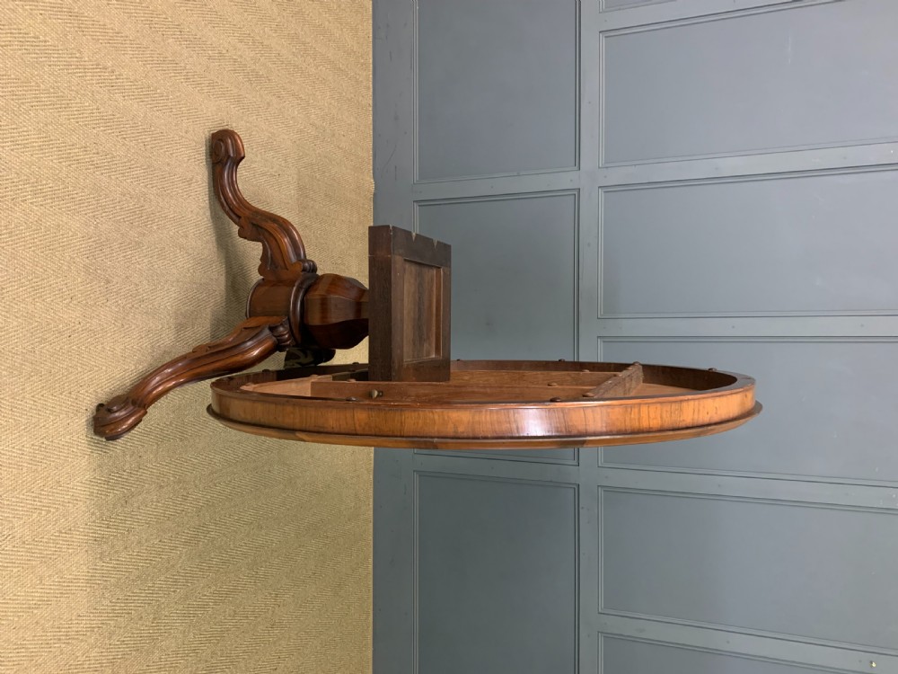 An oval Victorian rosewood loo table featuring a book-matched veneered top, crossbanded edge, and a carved central pedestal with four splayed legs on castors. View XIV