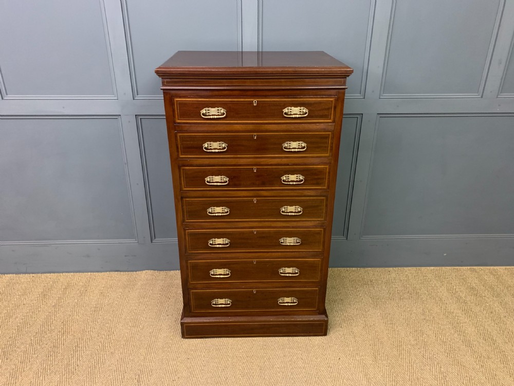 A tall Edwardian mahogany pillar chest featuring seven inlaid drawers with brass drop handles on a plinth base. View II