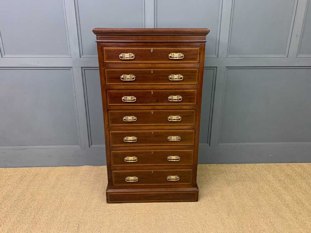 A tall Edwardian mahogany pillar chest featuring seven inlaid drawers with brass drop handles on a plinth base. View III